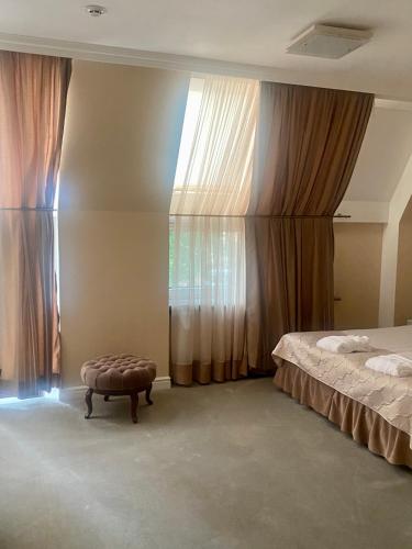a bedroom with a bed and a ottoman next to a window at Boutique Hotel Deluxe in Kamianets-Podilskyi