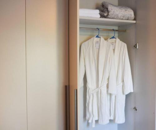 um armário com roupas brancas penduradas num cabide em Thematic beach apartment in CapCana area em Punta Cana
