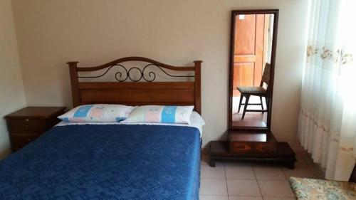 a bedroom with a bed with a blue blanket and a mirror at Residencial Teresita in Vallegrande