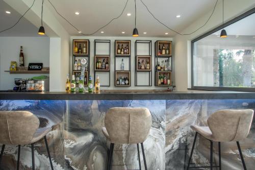 a bar with three stools in front of a fish tank at Lardos Bay Hotel in Lardos