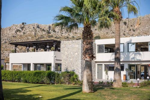 una casa con palmeras delante en Lardos Bay Hotel, en Lardos