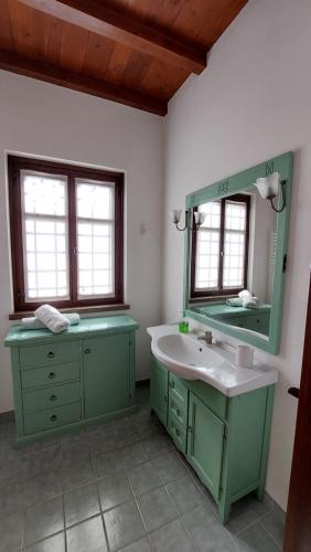 uma casa de banho verde com um lavatório e um espelho em DOMUS AETRURIAE (ETRURIE) em Bracciano