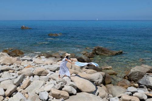 a woman in a white dress walking on a rocky beach at Infinity Resort Tropea in Parghelia