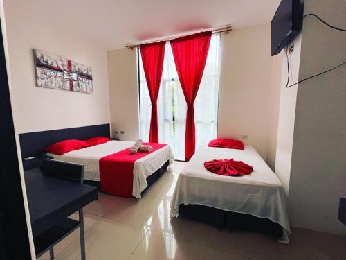 a room with two beds and a window with red curtains at HOTEL AMASH Chone in San Pablo