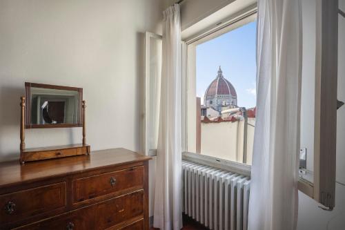Cette chambre dispose d'une fenêtre, d'une commode et d'un miroir. dans l'établissement Apartment with terrace facing Duomo, à Florence