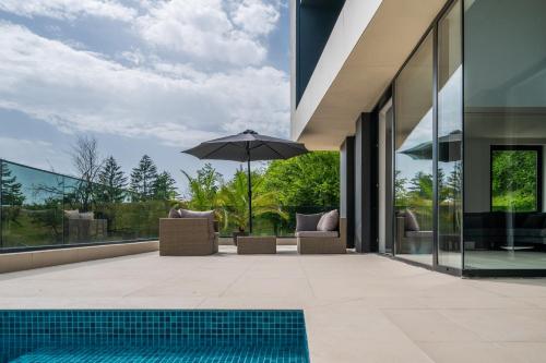 a swimming pool with an umbrella next to a house at The Villa O in Sarajevo
