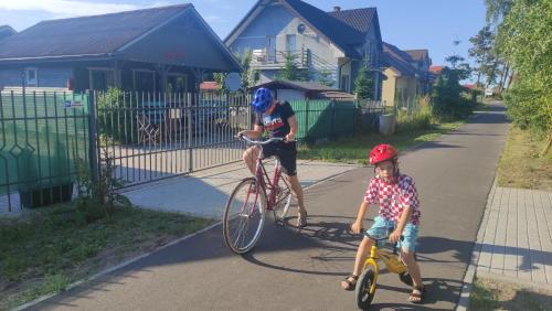 a man riding a bike next to a little boy at Na Fali Domki Letniskowe in Żarnowska