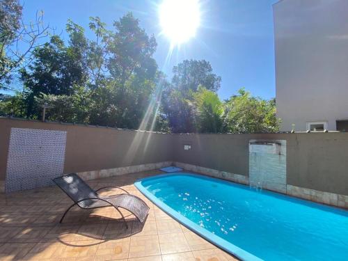 a swimming pool with a chair and the sun at Linda casa Condomínio Costa do Sol - Bertioga in Bertioga