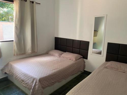 a bedroom with two beds and a mirror at Linda casa Condomínio Costa do Sol - Bertioga in Bertioga