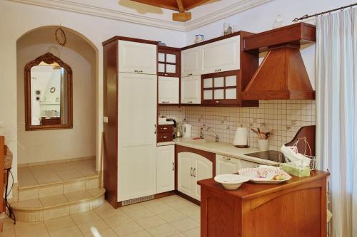 a kitchen with white cabinets and a sink and a mirror at Albatros Villa in Alonnisos