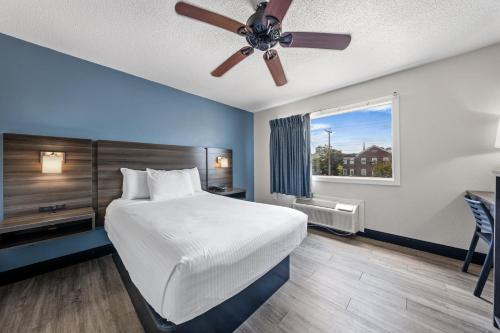 a bedroom with a large bed with a ceiling fan at SureStay Hotel by Best Western Virginia Beach Royal Clipper in Virginia Beach