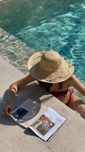 a woman wearing a straw hat sitting next to a swimming pool at Agriturismo Colle Igino in Matera