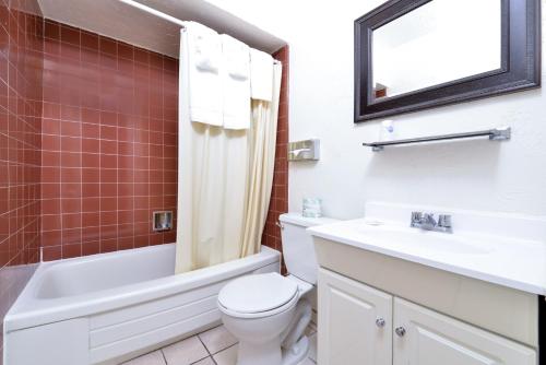 a bathroom with a toilet and a sink and a mirror at Americas Best Value Inn Loma Lodge in San Diego
