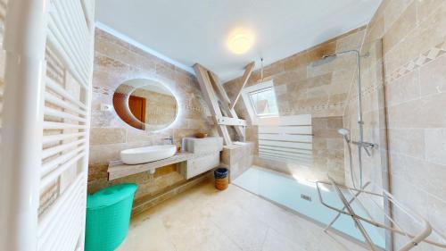 een badkamer met een wastafel, een spiegel en een douche bij Le Clos de Charlotte in Colmar