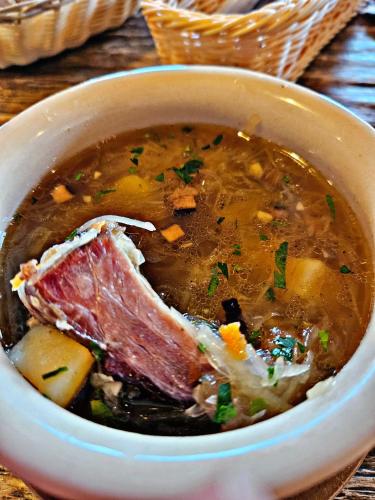 a bowl of soup with meat and vegetables on a table at Hotel Villa Siesta in Smokovce