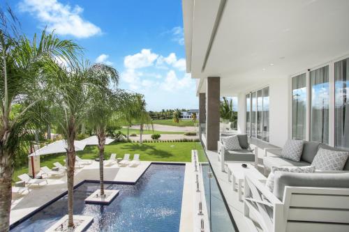 - un salon avec une piscine et des palmiers dans l'établissement Exquisite Contemporary 8BR Pool Villa with Chef, Butler, Maid, and Eden Roc Beach Club Access, à Punta Cana