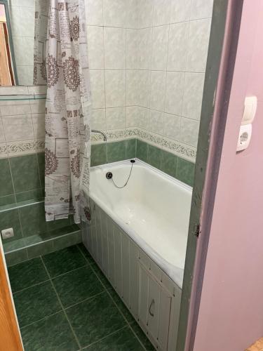 a bath tub in a bathroom with green tiles at saules street apartment in Ventspils