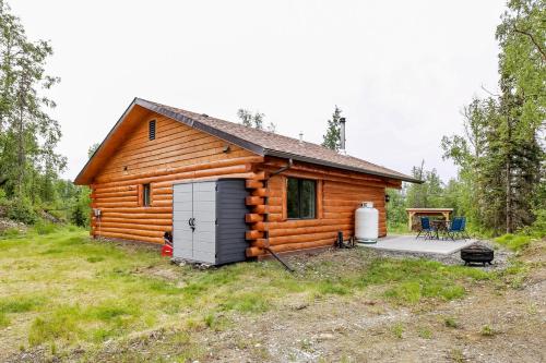 a log cabin with a garage in the yard at Welcoming Wasilla Cabin with Patio! in Wasilla