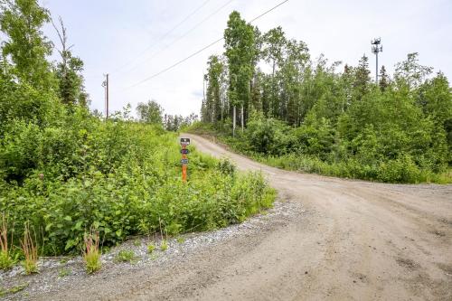 a dirt road next to a field with trees at Welcoming Wasilla Cabin with Patio! in Wasilla