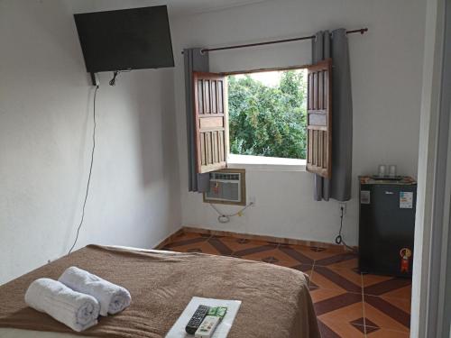 a bedroom with a bed and a window and a television at Aluguel de suites e Apartamento in Itacaré