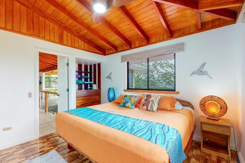 een slaapkamer met een bed en een houten plafond bij Casa Garrobo in Dominical
