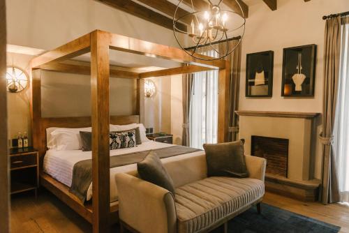 a bedroom with a canopy bed and a chair at Hotel Apapacho Boutique in San Miguel de Allende