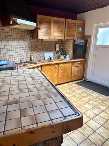 a kitchen with wooden cabinets and a tiled floor at Bien-être-Au-calme et parking gratuit in Seraing