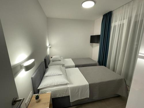 two beds in a small hotel room with a desk and a bed at Markioli Residence in Sevid