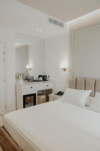 a white bedroom with a bed and a fireplace at Seaside Hotel in Vlorë