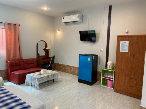 een woonkamer met een bank, een tafel en een tv bij บุญจินดา รีสอร์ท in Ban Phayom