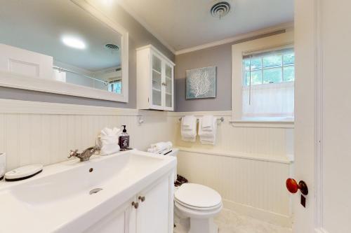 a white bathroom with a sink and a toilet at Garden Cottage By The Sea in Manchester