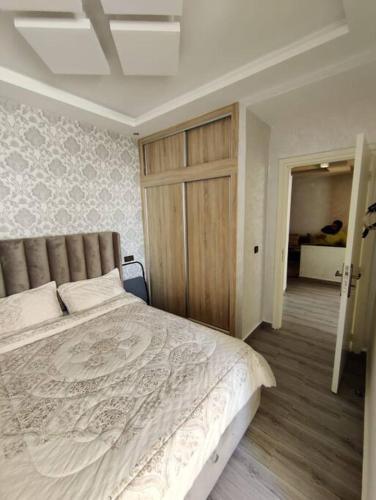 een slaapkamer met een groot bed en een houten deur bij Very Nice Relaxing Apartment In Agadir El Houda in Agadir