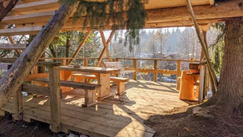 a porch of a cabin with a table and a tree at Get your zen among the trees in Stahovica