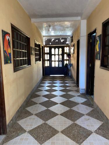pasillo con suelo a cuadros y puerta en Hostal Yahuarcaca, en Leticia