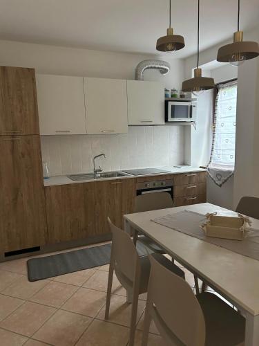 a kitchen with white cabinets and a table and chairs at la tana del viaggiatore in Cavedago