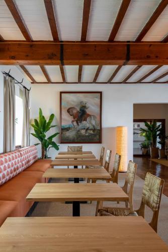 a room with wooden tables and chairs and a painting at Parador de Mazagón in Mazagón