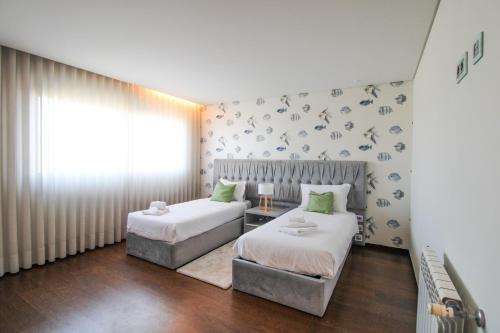 Un dormitorio con dos camas y una ventana en Ocean View Luxury Apartment, en Vila Nova de Gaia
