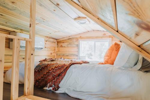 a bed in a tiny house with a wooden ceiling at Hollow Hills Tiny Home in Penn Yan
