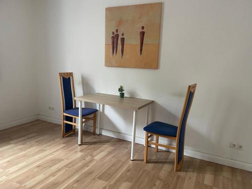 einen Tisch und zwei Stühle und ein Gemälde an der Wand in der Unterkunft Schönes einfaches Zimmer im belebten Zentrum in Wilhelmshaven