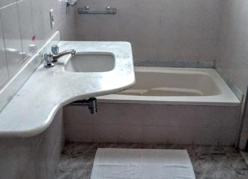 a bathroom with a sink and a bath tub at Hotel Bragança in Caxambu