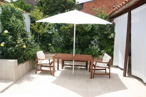 Casa Rural Mijarra **** في Herrera del Duque: طاولة خشبية مع كرسيين ومظلة