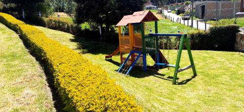 a playground in a field of yellow flowers at Apartamento - ApartaSuite ARGUS in Paipa
