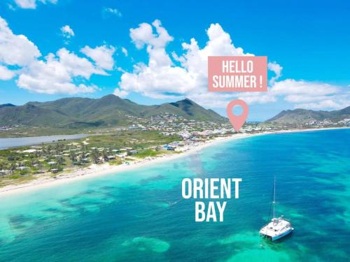 a boat in the ocean next to a beach at Hello Summer large studio on Orient Bay beach in Orient Bay