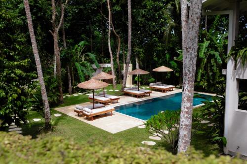 a swimming pool with chairs and umbrellas next to a resort at The Nook RESORT in Devinuwara