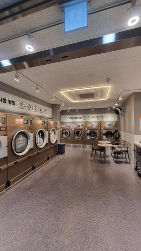 a laundry room with multiple washing machines and tables at Daegu StarB&B DSR Hotel mia Guestroom in Daegu