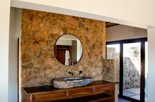 Baño de piedra con lavabo y espejo en Sibani Lodge, en Krugersdorp