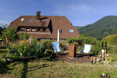 a house with two lawn chairs and a garden at SchwarzWild - Ferienwohnung und Ferienzimmer in Baiersbronn