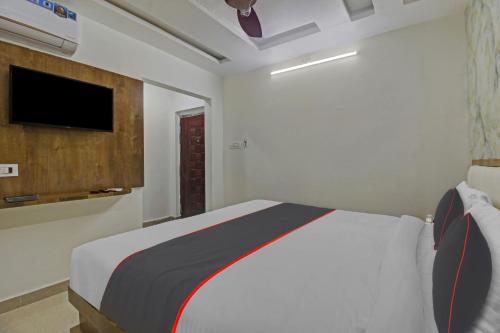 1 dormitorio con 1 cama y TV de pantalla plana en Vinayaka Luxury Stays, en Warangal
