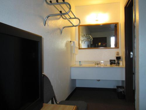 a bathroom with a sink and a mirror and a tv at Motel 10 in Lordsburg