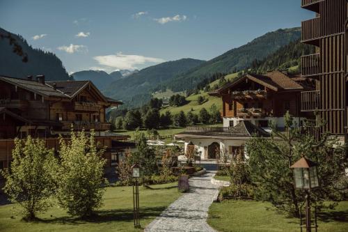 a pathway in a village with houses and mountains at Familien Natur Resort Moar Gut in Grossarl